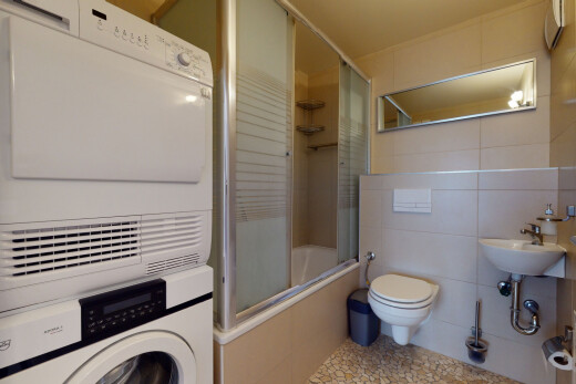 salle de bains avec tile wall, mur en carrelage, lave-linge et sèche-linge superposés, douche-bain combinés, et toilette