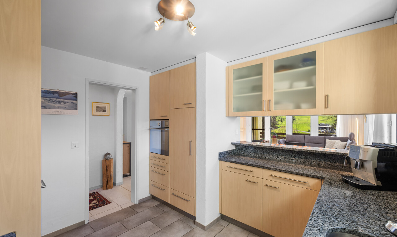 küche mit two heights countertops, dark countertops, schränke mit glastüren, glass insert cabinets, und hellbraune schränke