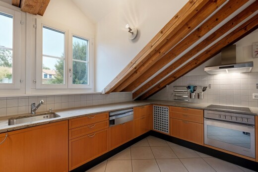 kitchen with wall chimney range hood, stainless steel oven, backsplash, lofted ceiling, and light tile patterned floors