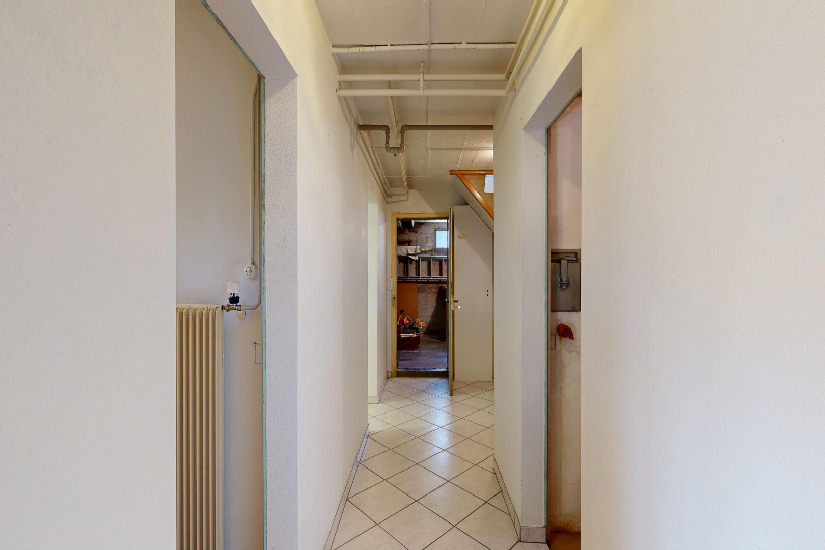 couloir avec cloison sèche, drywall, radiateur, inside property, et sol en carrelage