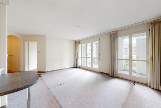 carpeted spare room featuring arched walkways and baseboards