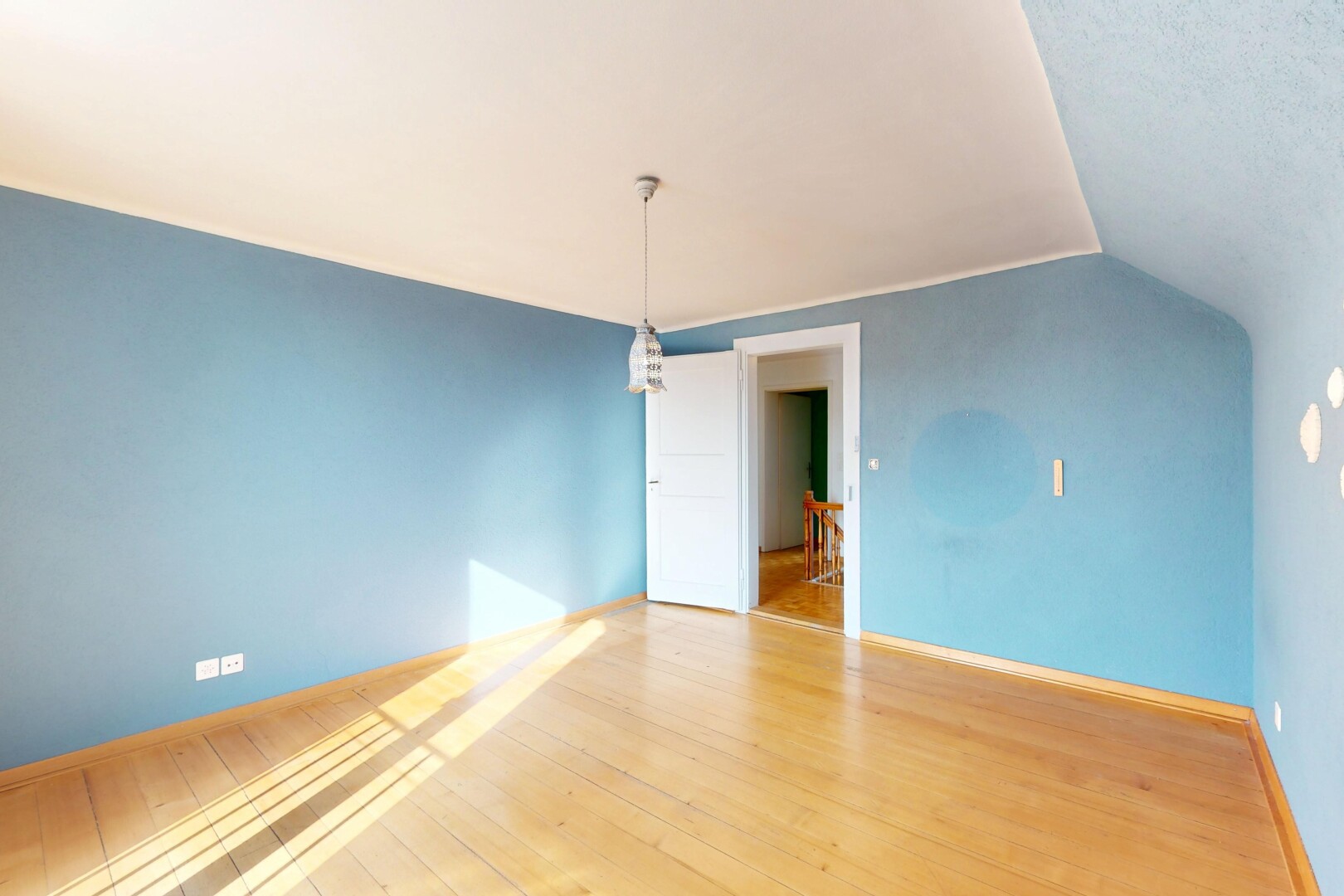 pièce vide avec cloison sèche, plinthes murales, plafond voûté, et sol en finition bois