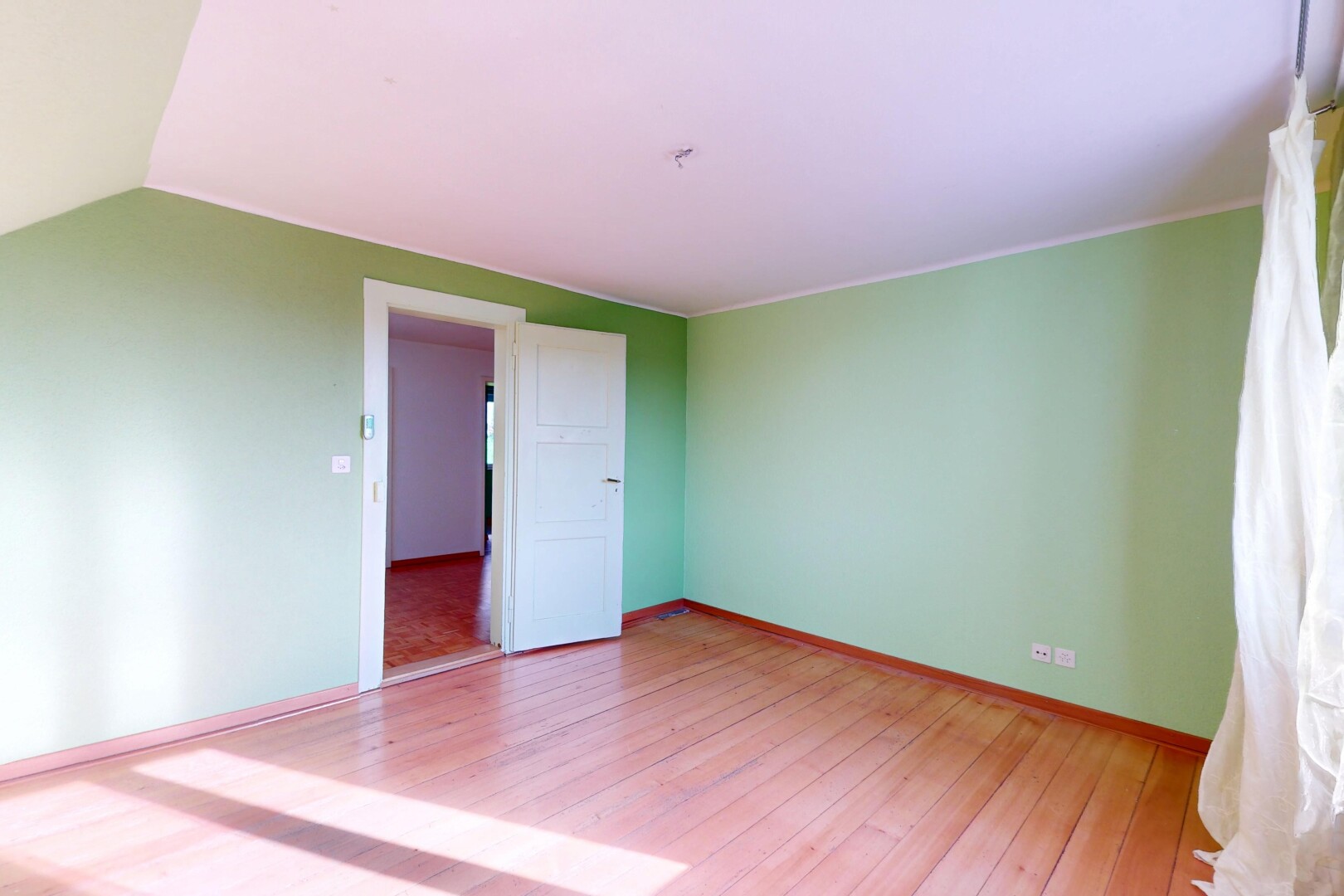 pièce vide avec plafond voûté, cloison sèche, plinthes murales, et sol en finition bois