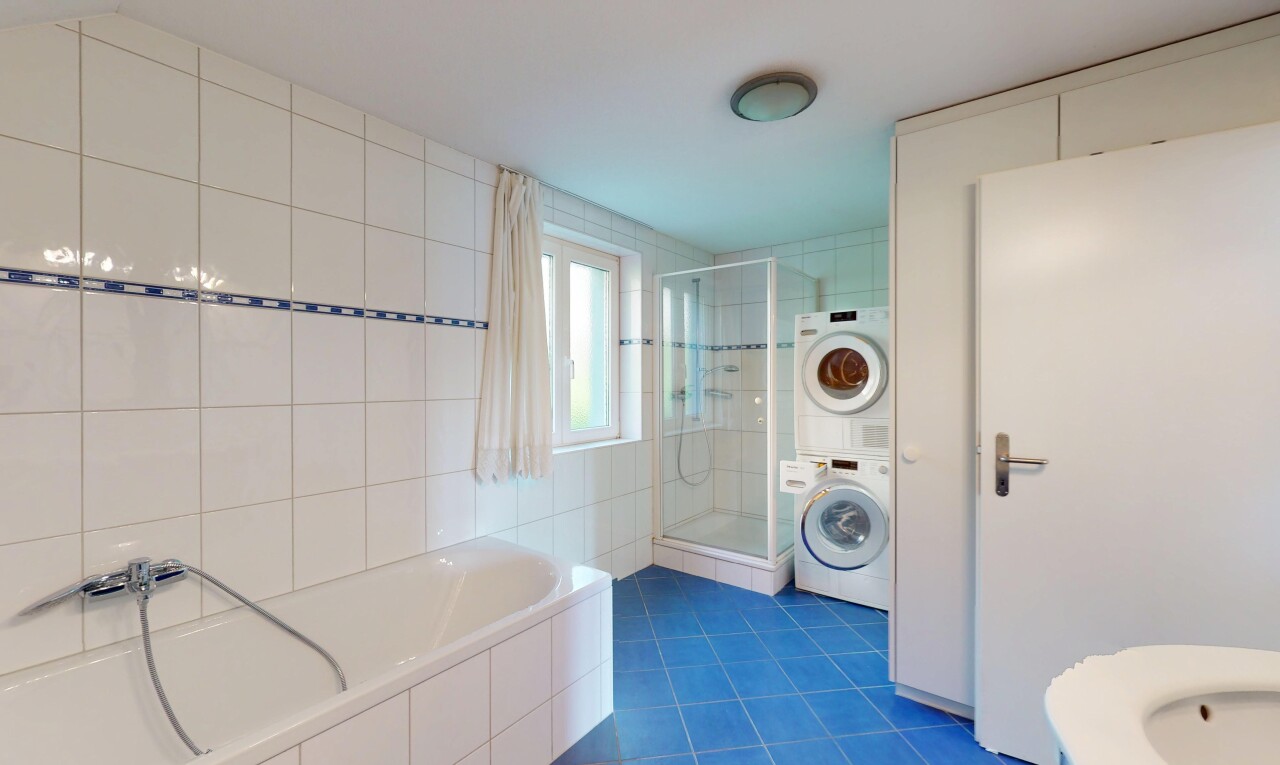 salle de bains avec douche, lave-linge et sèche-linge superposés, bain, sol en carrelage, et lumière naturelle