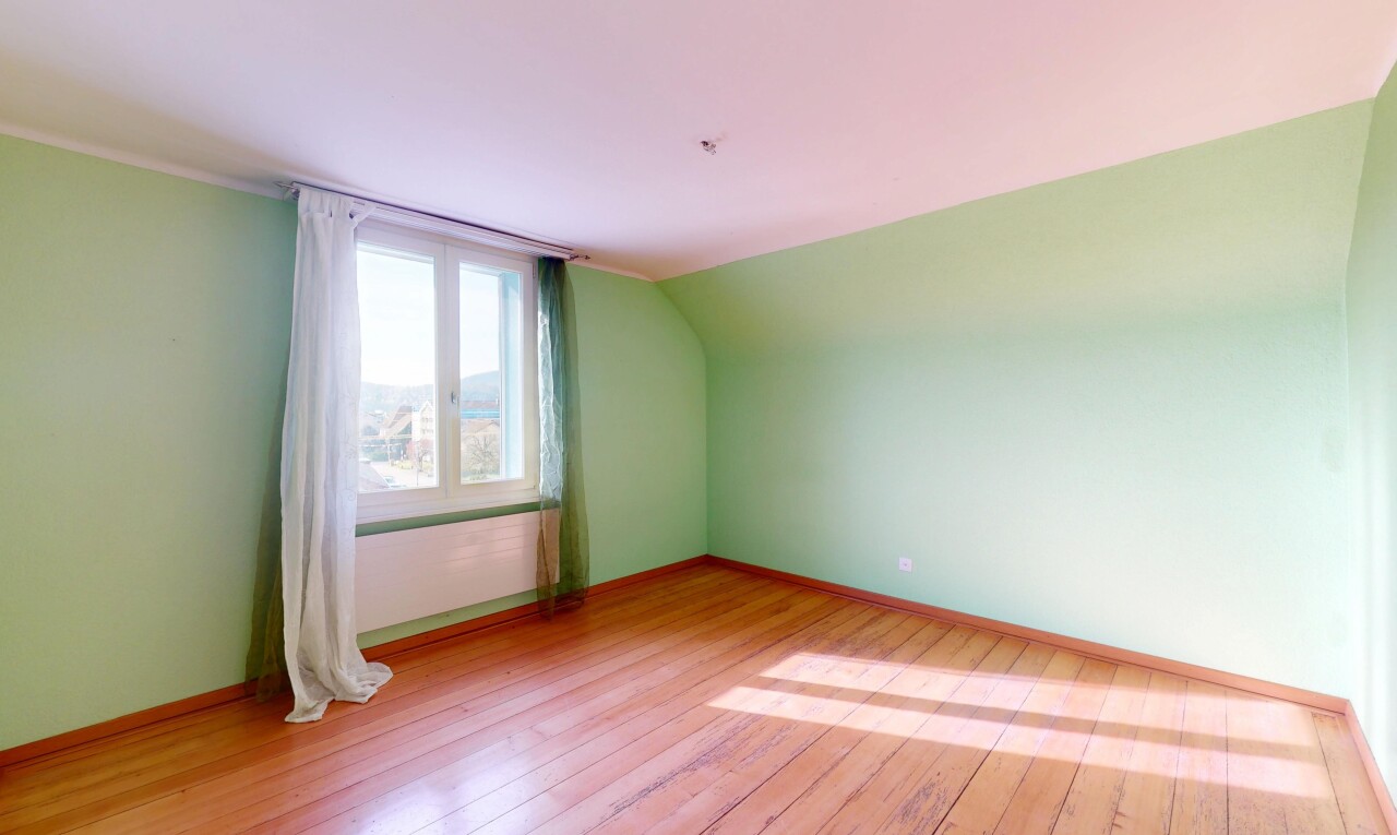 pièce vide avec sol en finition bois, cloison sèche, plinthes murales, lumière naturelle, et plafond bas
