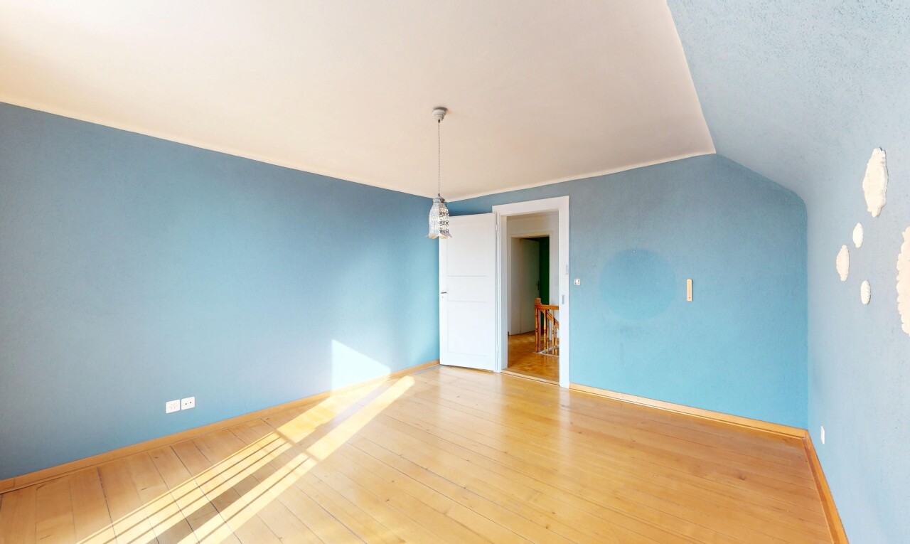 pièce vide avec cloison sèche, plinthes murales, plafond voûté, et sol en finition bois