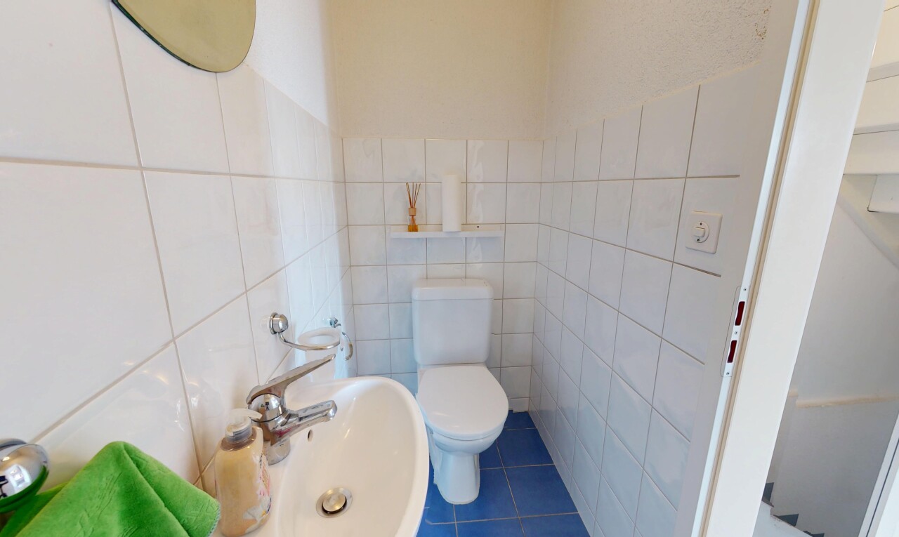 salle de bains avec mur en carrelage, toilette, évier, et sol en carrelage