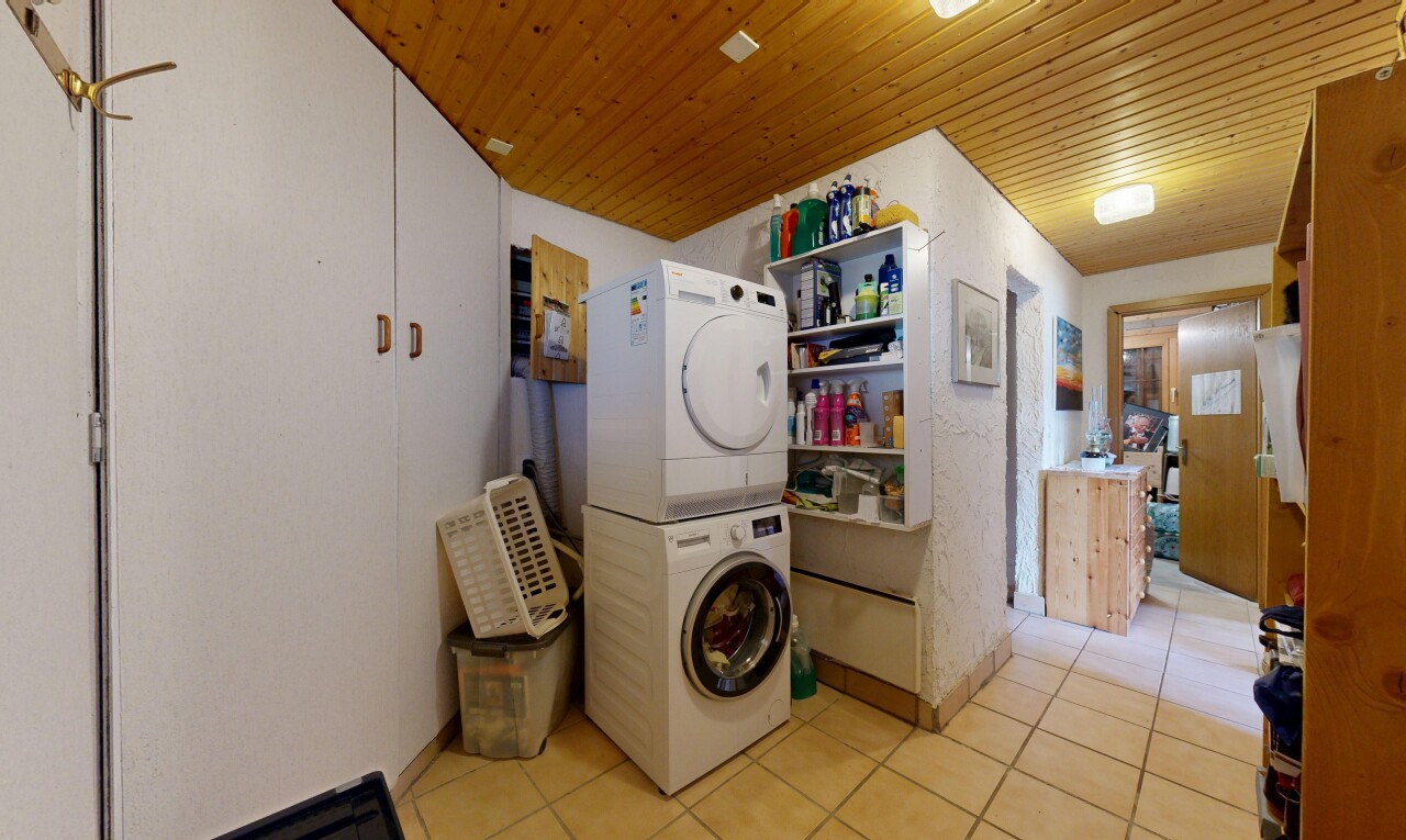 laundry area featuring light tile patterned floors, stacked washer and clothes dryer, and wood ceiling