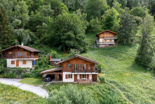 view of home with a balcony, a lawn, a carport, and a view of trees