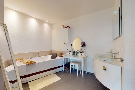 badezimmer mit fliesenböden, spiegel, großer waschtisch und badewanne