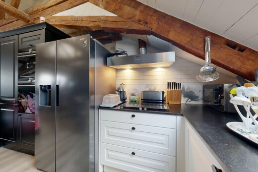 cuisine avec dark countertops, beamed ceiling, plafond à poutres, hotte, et armoires élevées