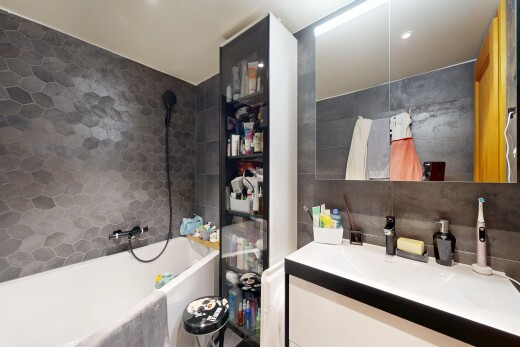 salle de bains avec mur en carrelage, tile wall, lavabo (ou coiffeuse selon le contexte), miroir, et salle de bain complète