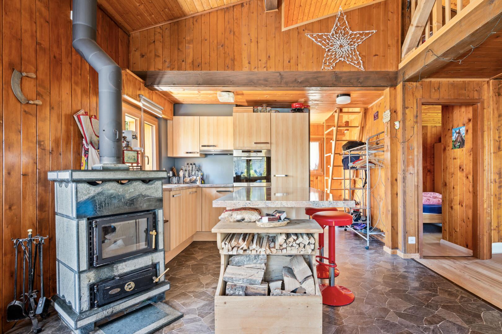 cuisine avec mur en bois, wood wall, plafond haut, high ceiling, et sol en finition pierre