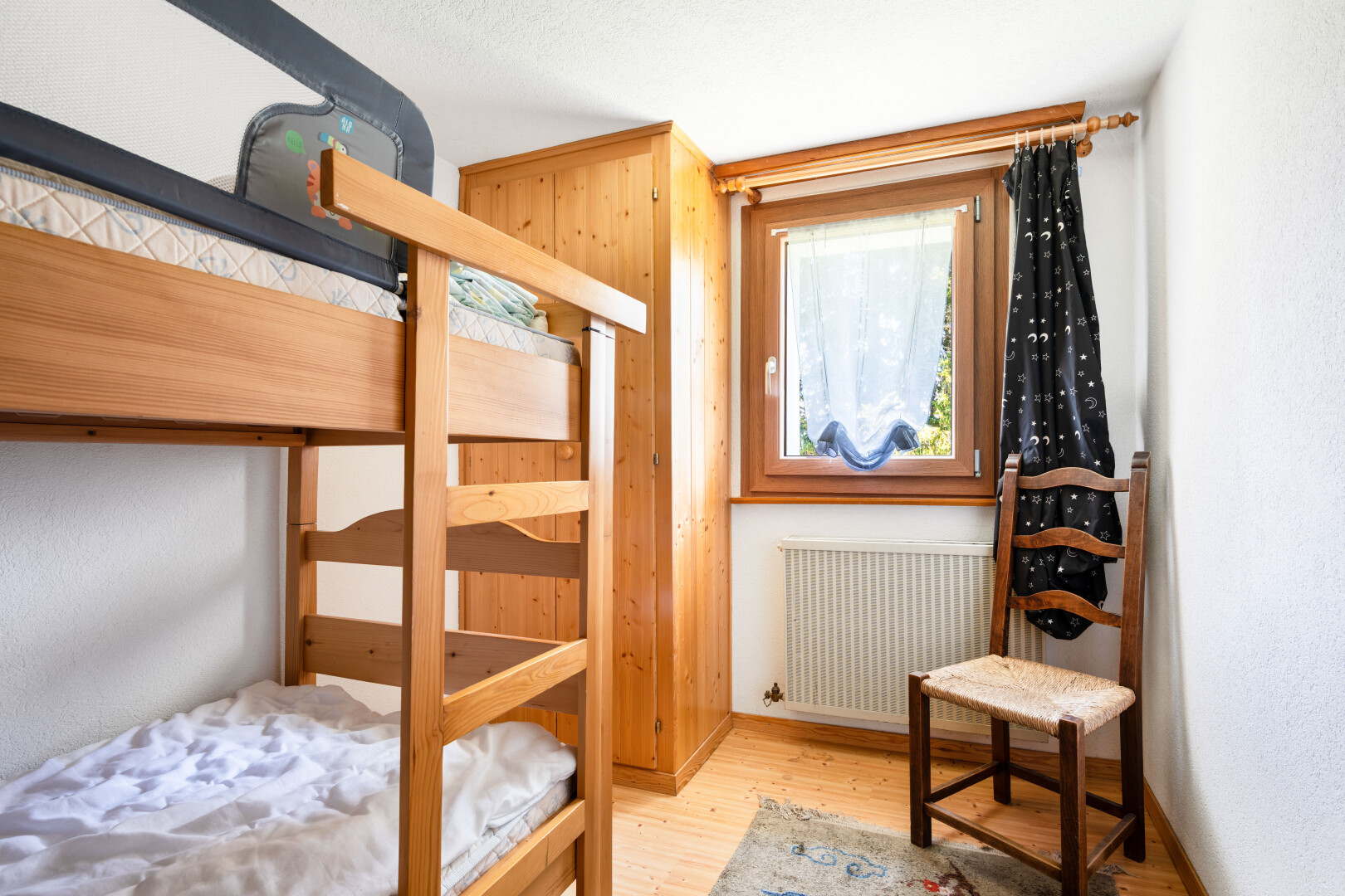 chambre avec radiateur, sol en finition bois, wood finish floor, inside property, et lumière naturelle