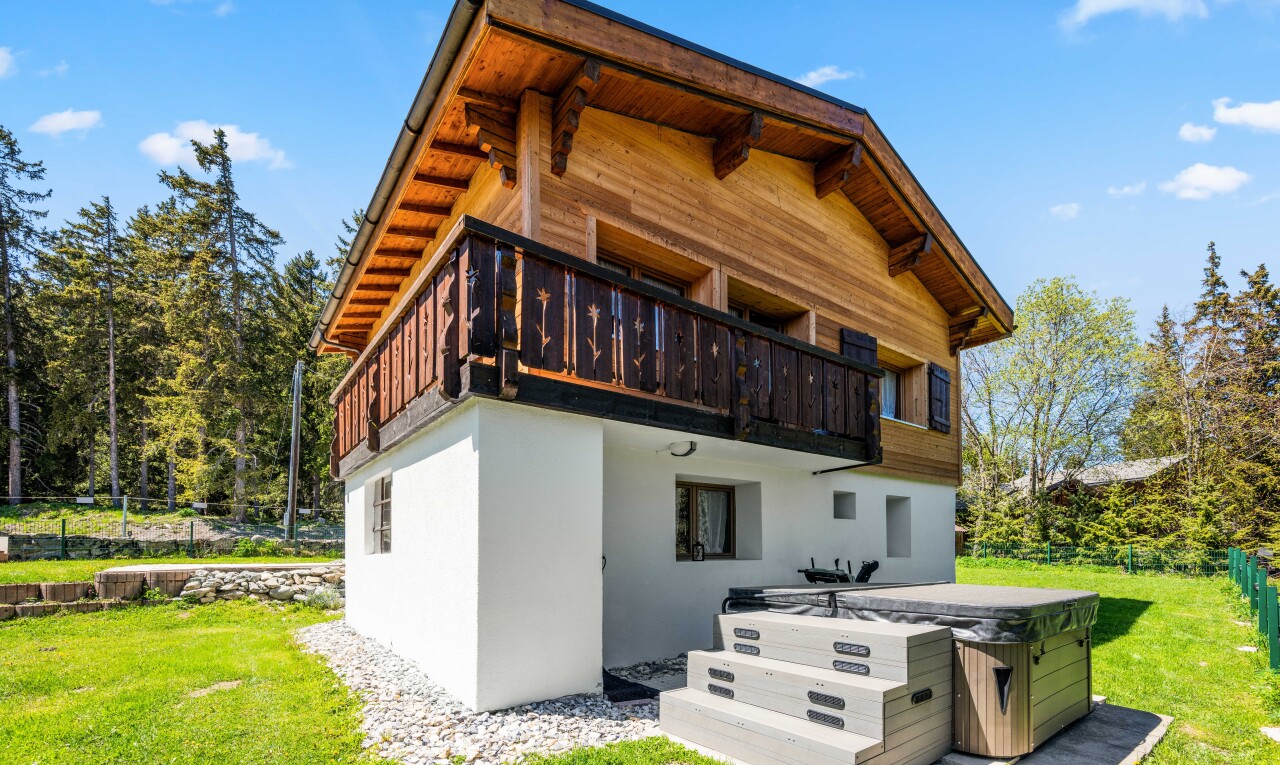 view of home with a lawn, a hot tub, a balcony, stucco siding, and a patio
