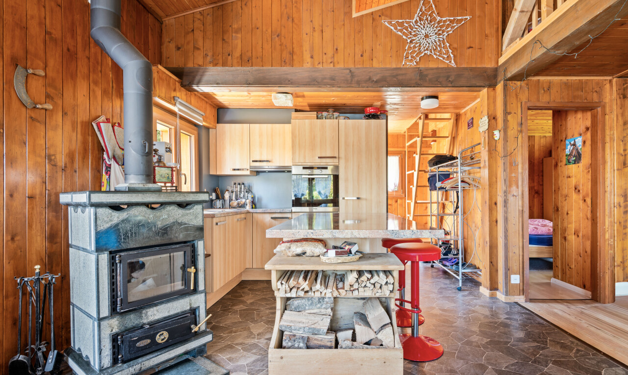 kitchen with wooden walls, stone floors, light wood finish cabinets, oven, and light countertops