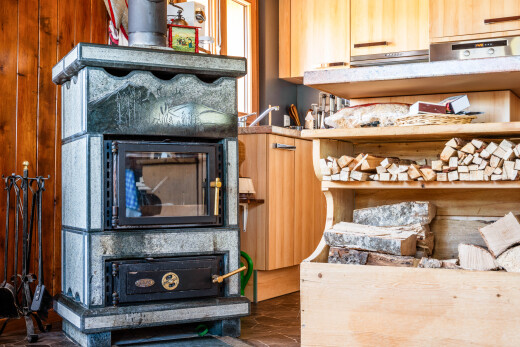 cuisine avec poêle à bois, inside property, sol en finition bois, wood finish floor, et armoires marron clair
