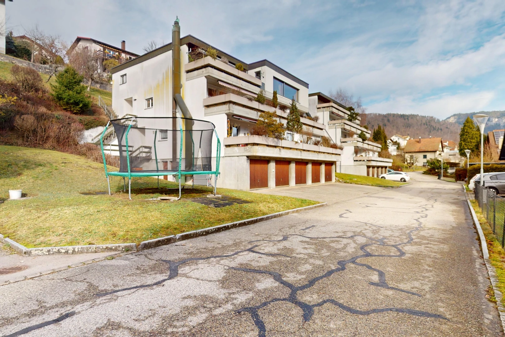 façade avec garage intégré, vue résidentielle, pelouse, et trampoline