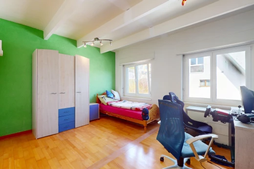 chambre avec poutres apparentes, télévision, plancher de bois, et lumière naturelle