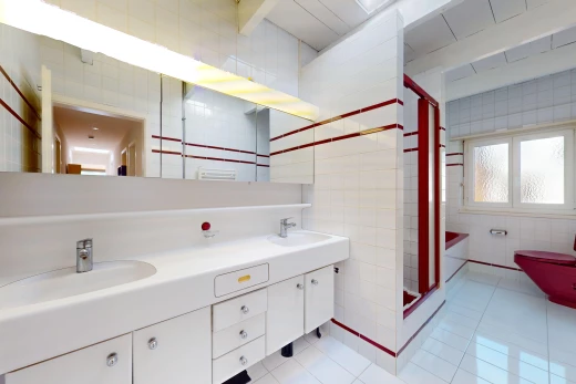 salle de bain avec double vasque, mur carrelé, meuble-lavabo, carrelage, et lumière naturelle