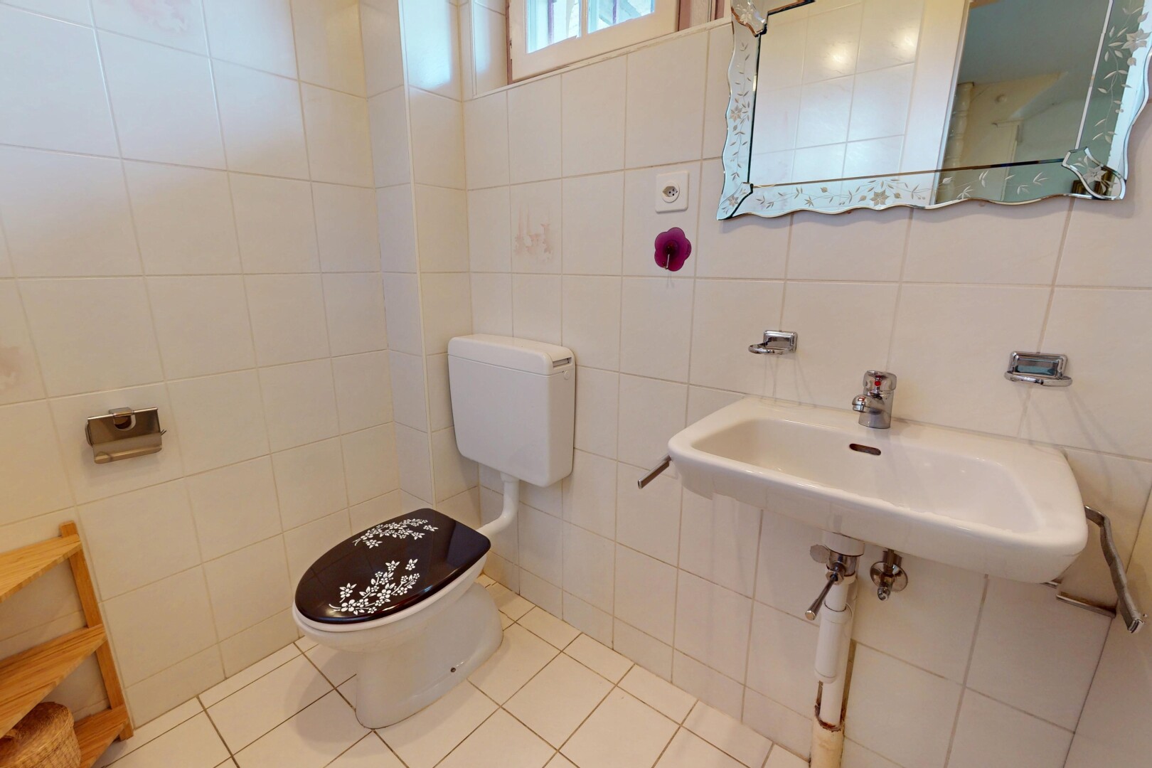 salle de bains avec toilettes, miroir, lumière naturelle, carrelage, et mur carrelé