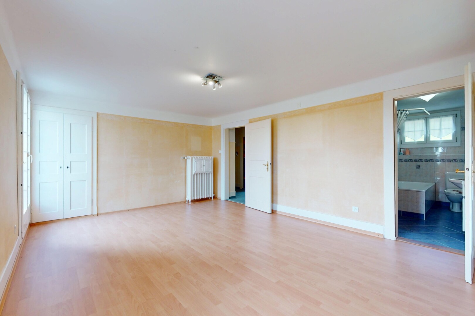 pièce vide avec radiateur, plancher de bois, et lumière naturelle