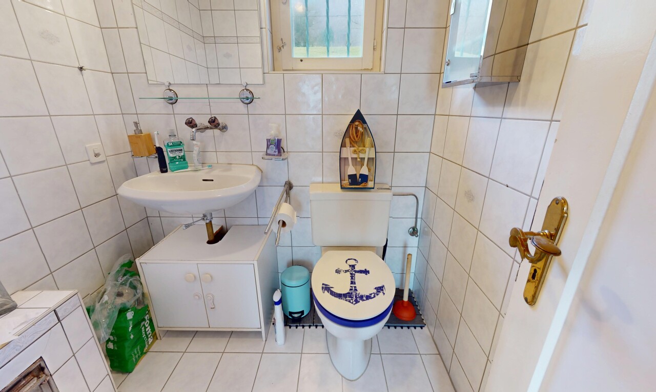 salle de bains avec lumière naturelle, mur carrelé, toilettes, et carrelage