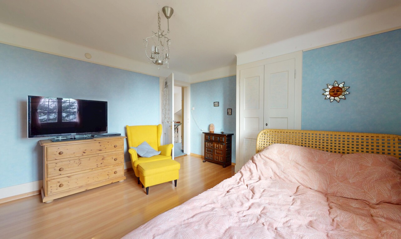 chambre avec lustre, plancher de bois, et télévision
