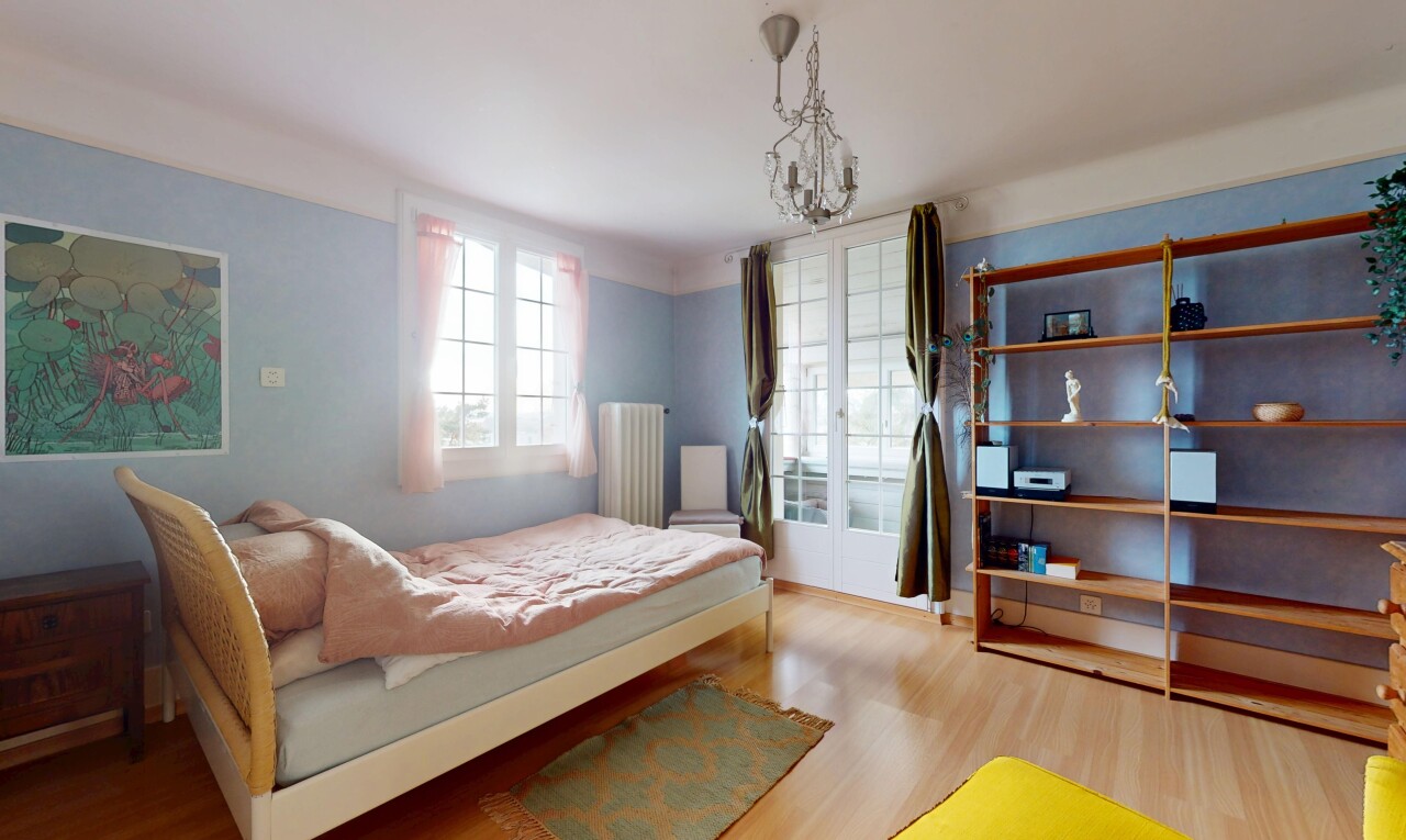chambre avec radiateur, plancher de bois, lumière naturelle, et lustre