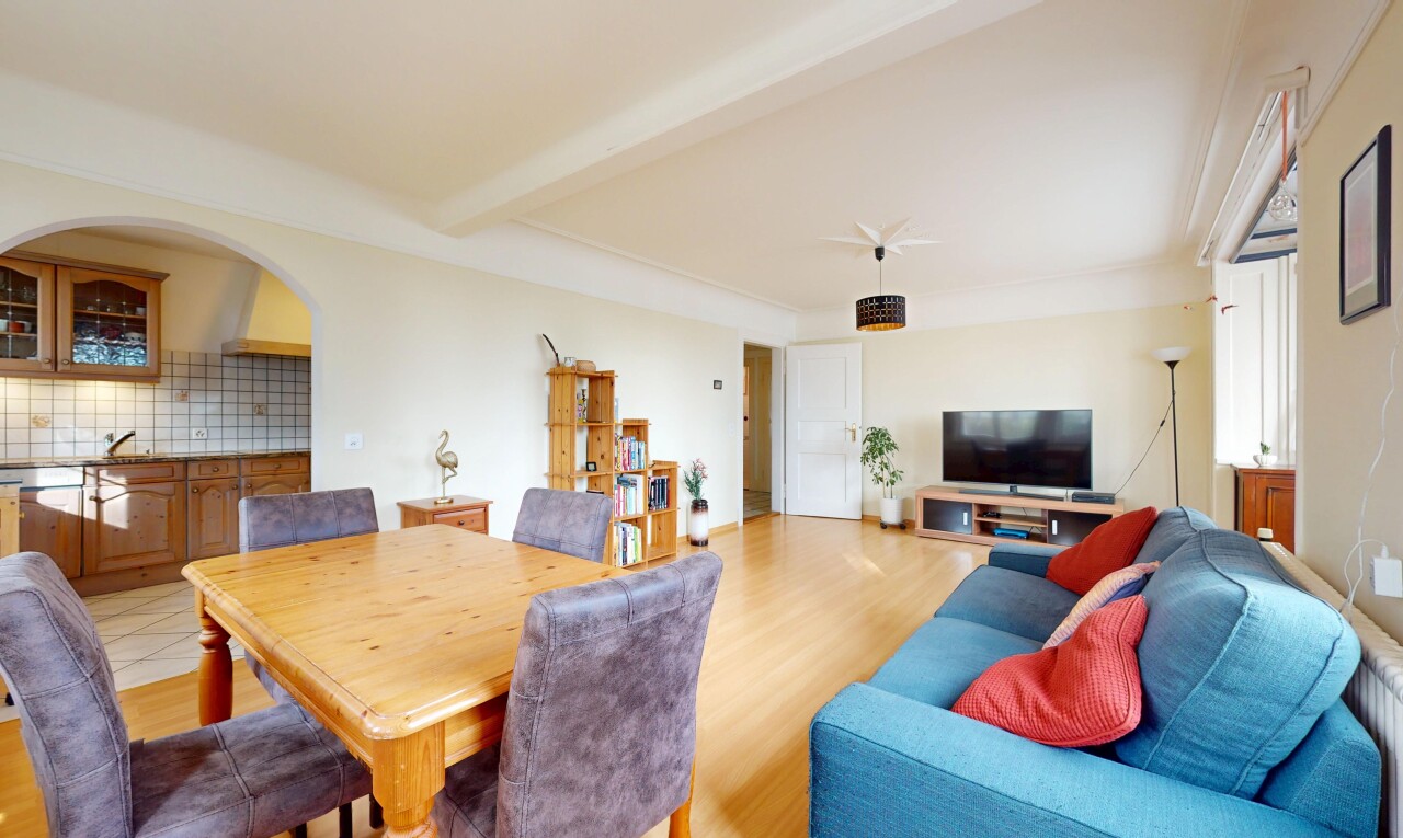 salon / salle à manger avec télévision, plancher de bois, et poutres apparentes