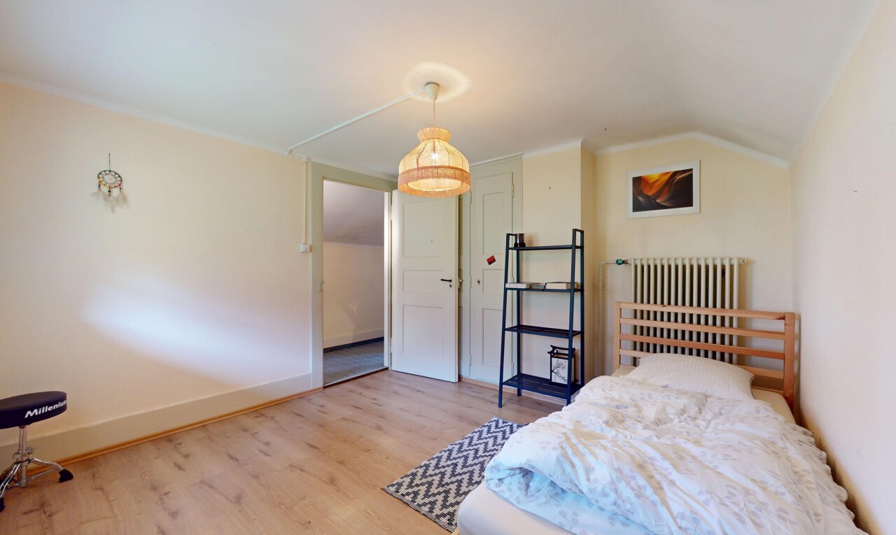 chambre avec radiateur, plafond voûté, et plancher de bois