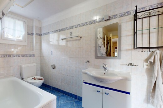 salle de bains avec mur carrelé, vasque, meuble-lavabo, toilettes, et miroir