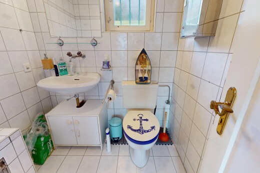 salle de bains avec lumière naturelle, mur carrelé, toilettes, et carrelage