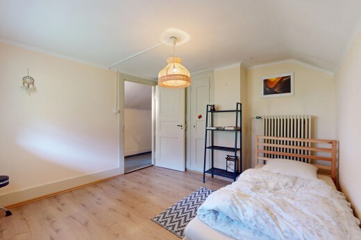 chambre avec radiateur, plafond voûté, et plancher de bois
