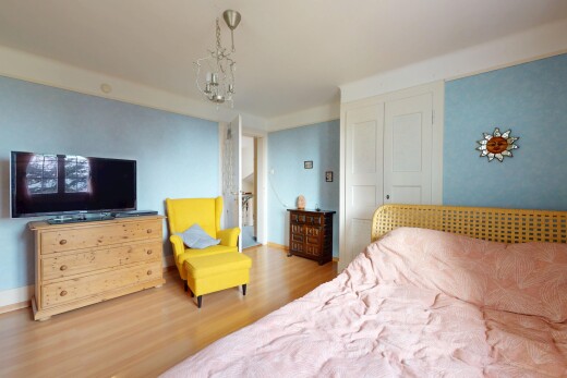 chambre avec lustre, plancher de bois, et télévision