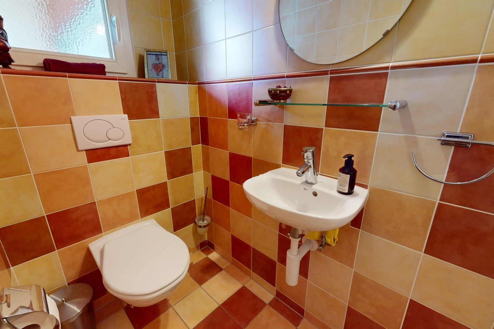 salle de bain avec mur carrelé, toilettes, miroir, et lumière naturelle