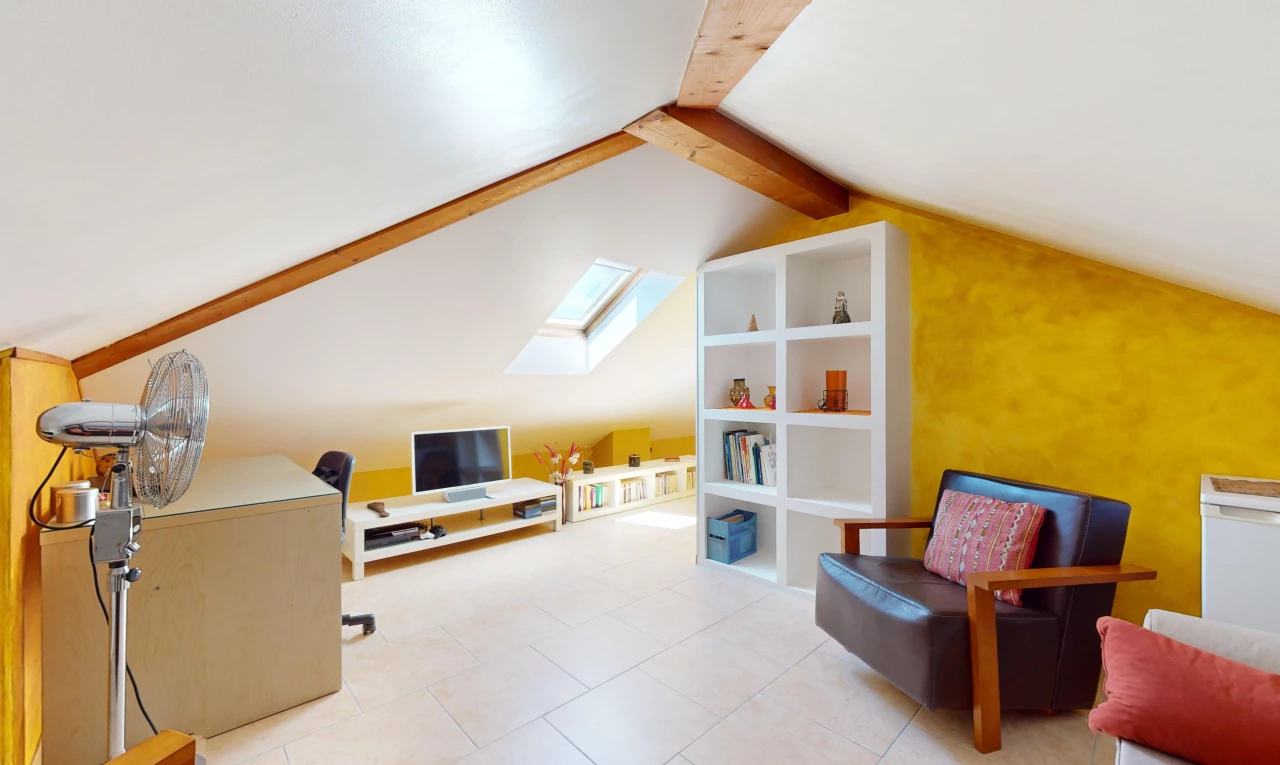 salon avec lucarne, carrelage, plafond voûté, lumière naturelle, et télévision