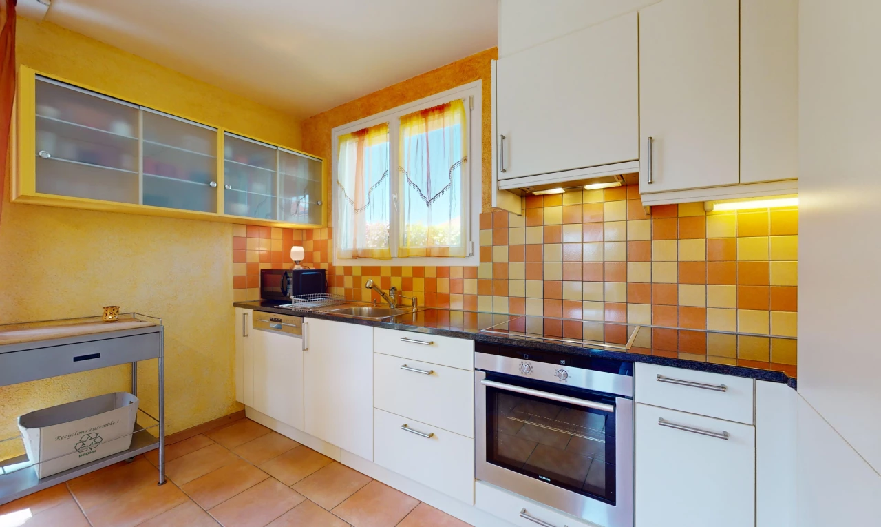 cuisine avec cuisinière, lumière naturelle, meubles blancs, et four