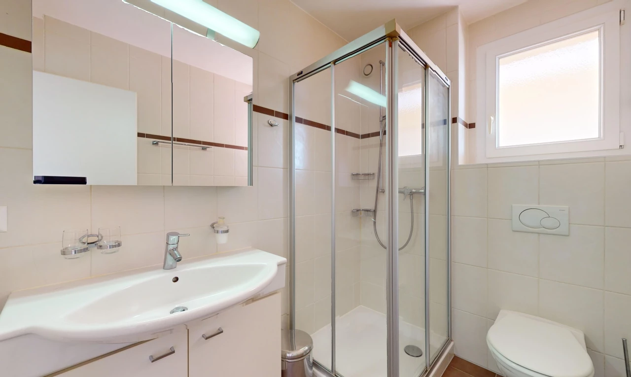 salle de bain avec miroir, mur carrelé, lumière naturelle, meuble-lavabo, et douche