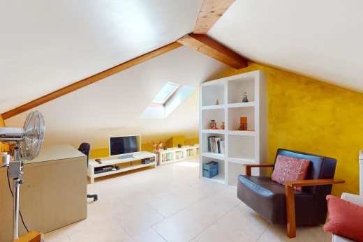 salon avec lucarne, carrelage, plafond voûté, lumière naturelle, et télévision
