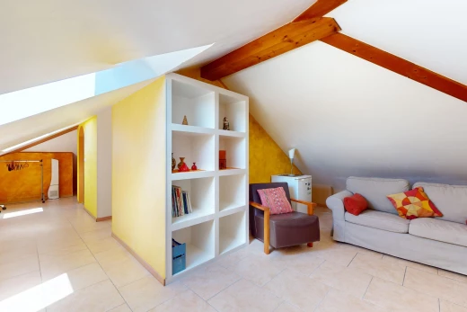 salon avec poutres apparentes, carrelage, étagère intégrée, plafond voûté, et plafond bas