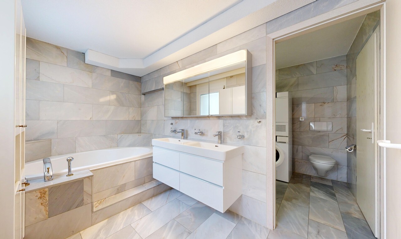 full bathroom with tile walls, double vanity, a garden tub, stacked washer and dryer, and light tile patterned flooring