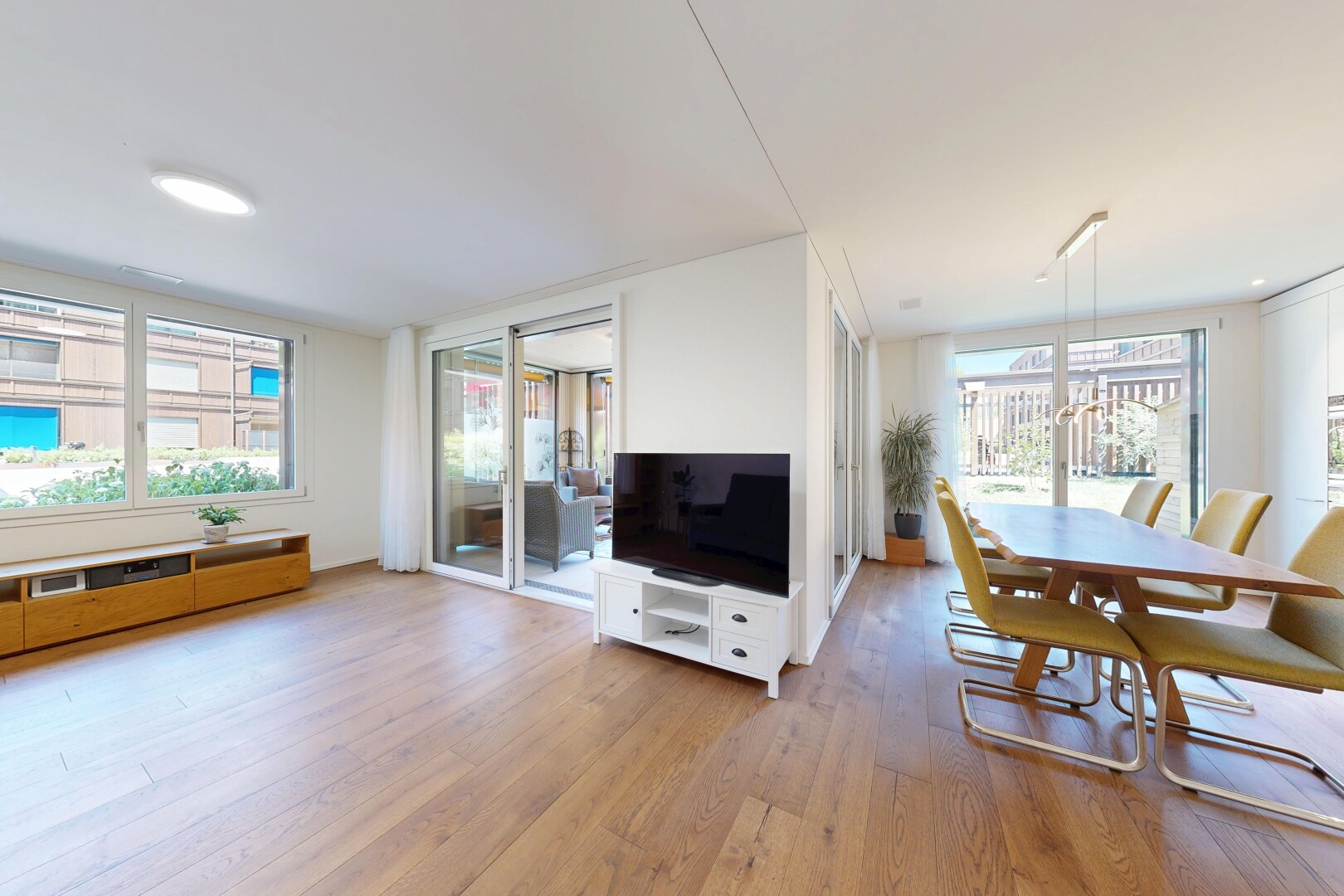 wohn- / esszimmer mit fernseher, holzfußboden, wood finish floor, gipskartonwand, und drywall