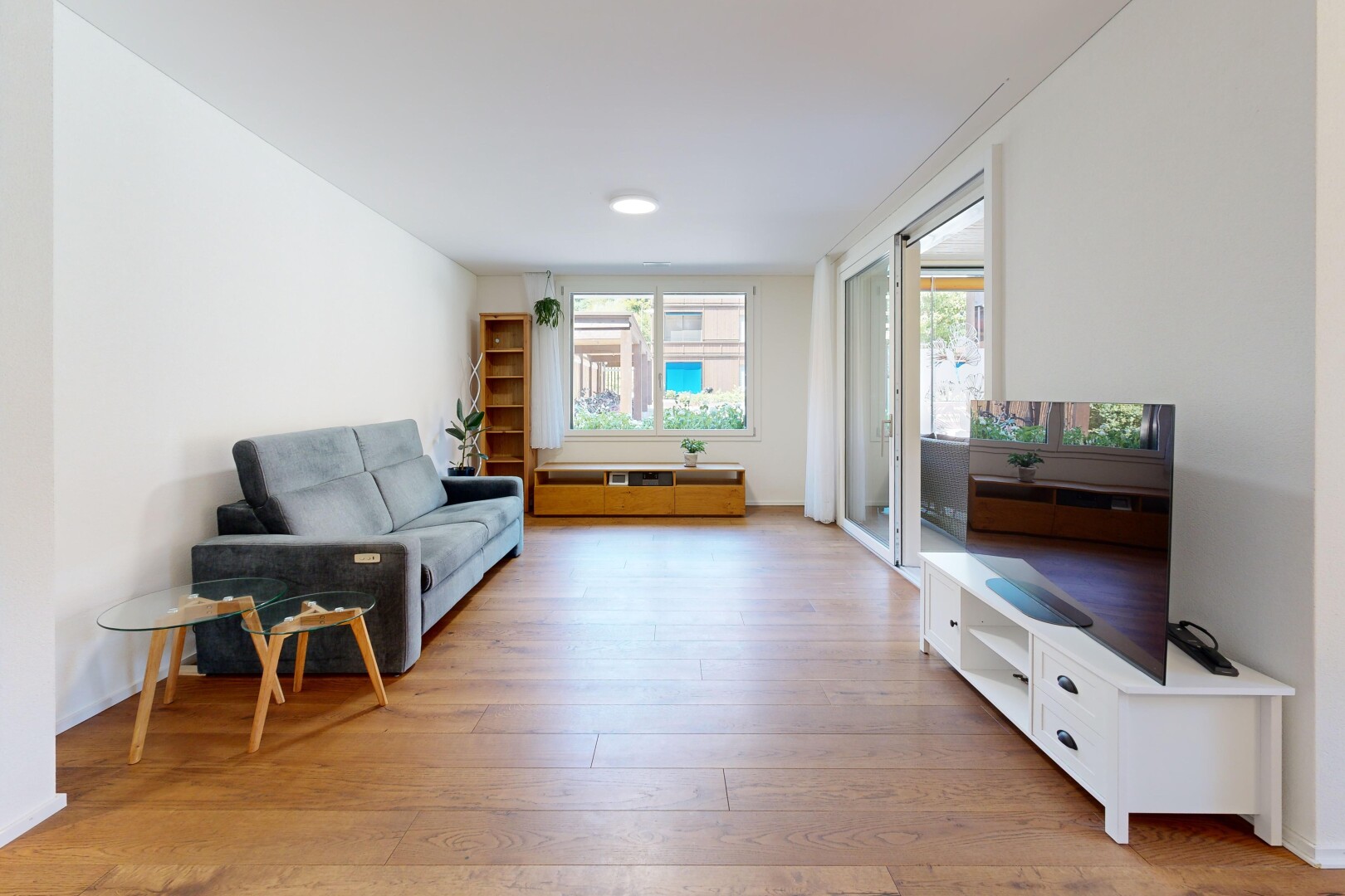 wohnzimmer mit fernseher, drywall, gipskartonwand, wood finish floor, und holzfußboden