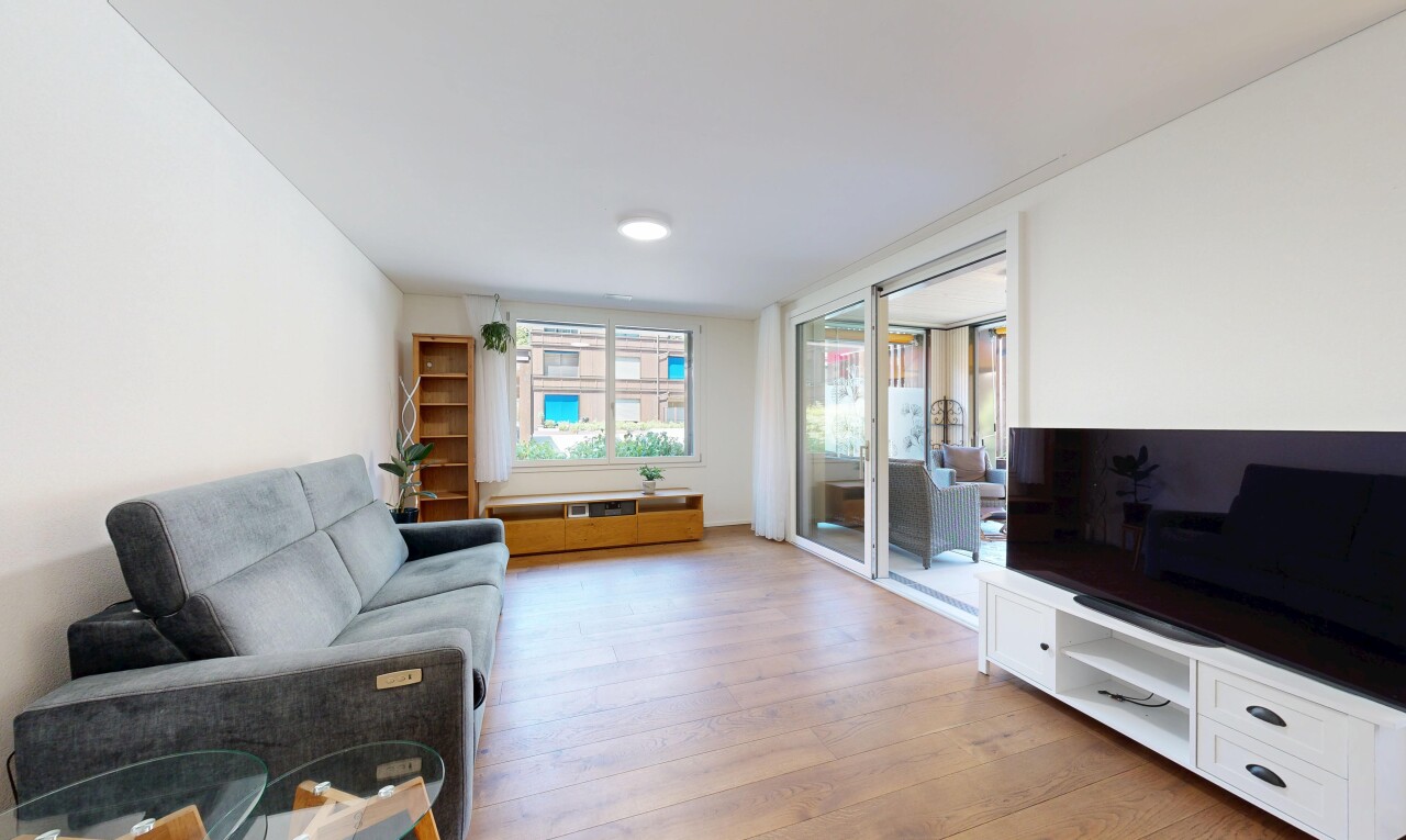 wohnzimmer mit fernseher, gipskartonwand, drywall, holzfußboden, und wood finish floor