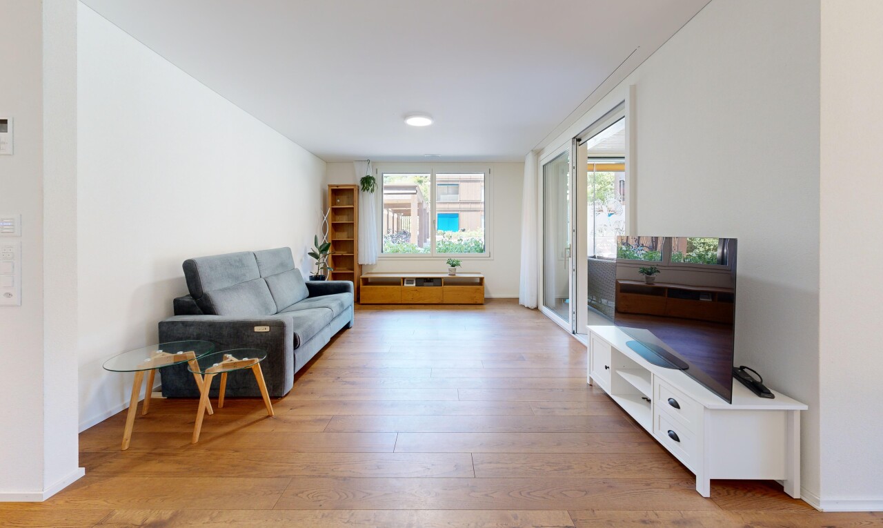 wohnzimmer mit fernseher, drywall, gipskartonwand, wood finish floor, und holzfußboden