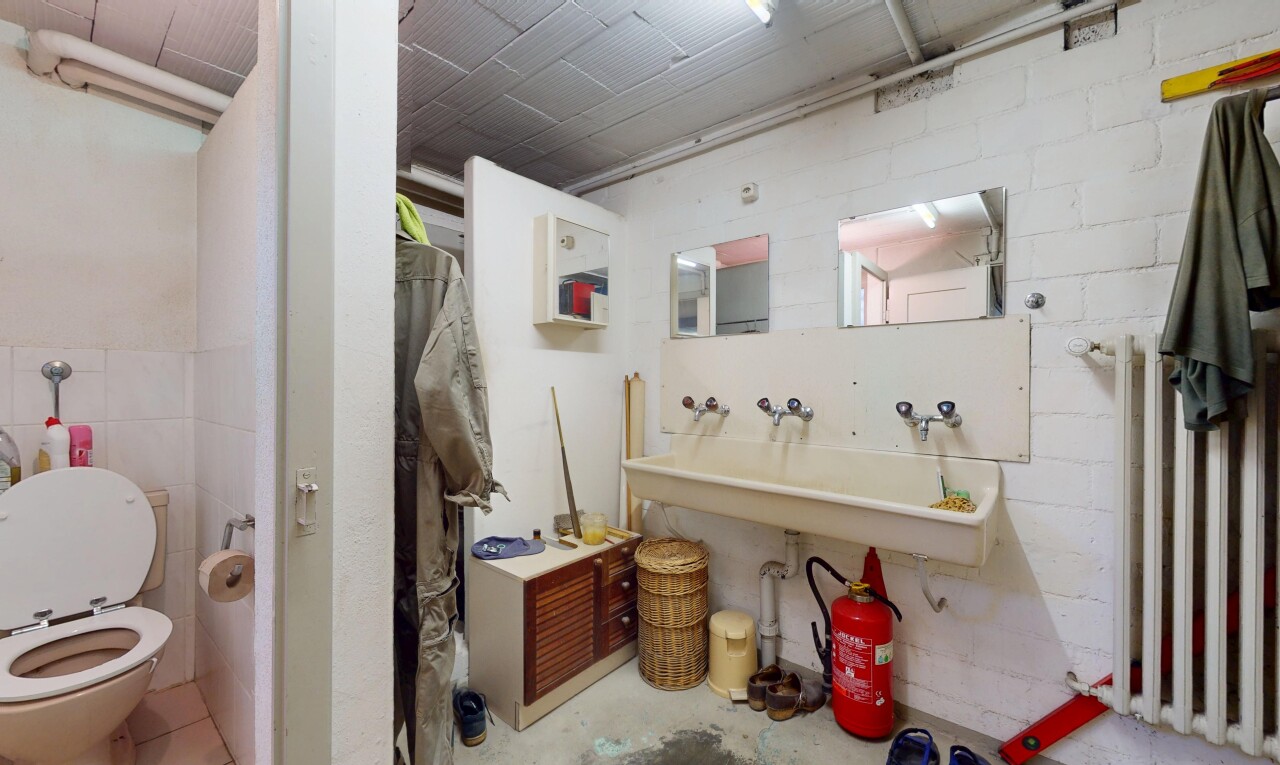 salle de bains avec toilette, miroir, inside property, concrete floor, et sol en béton