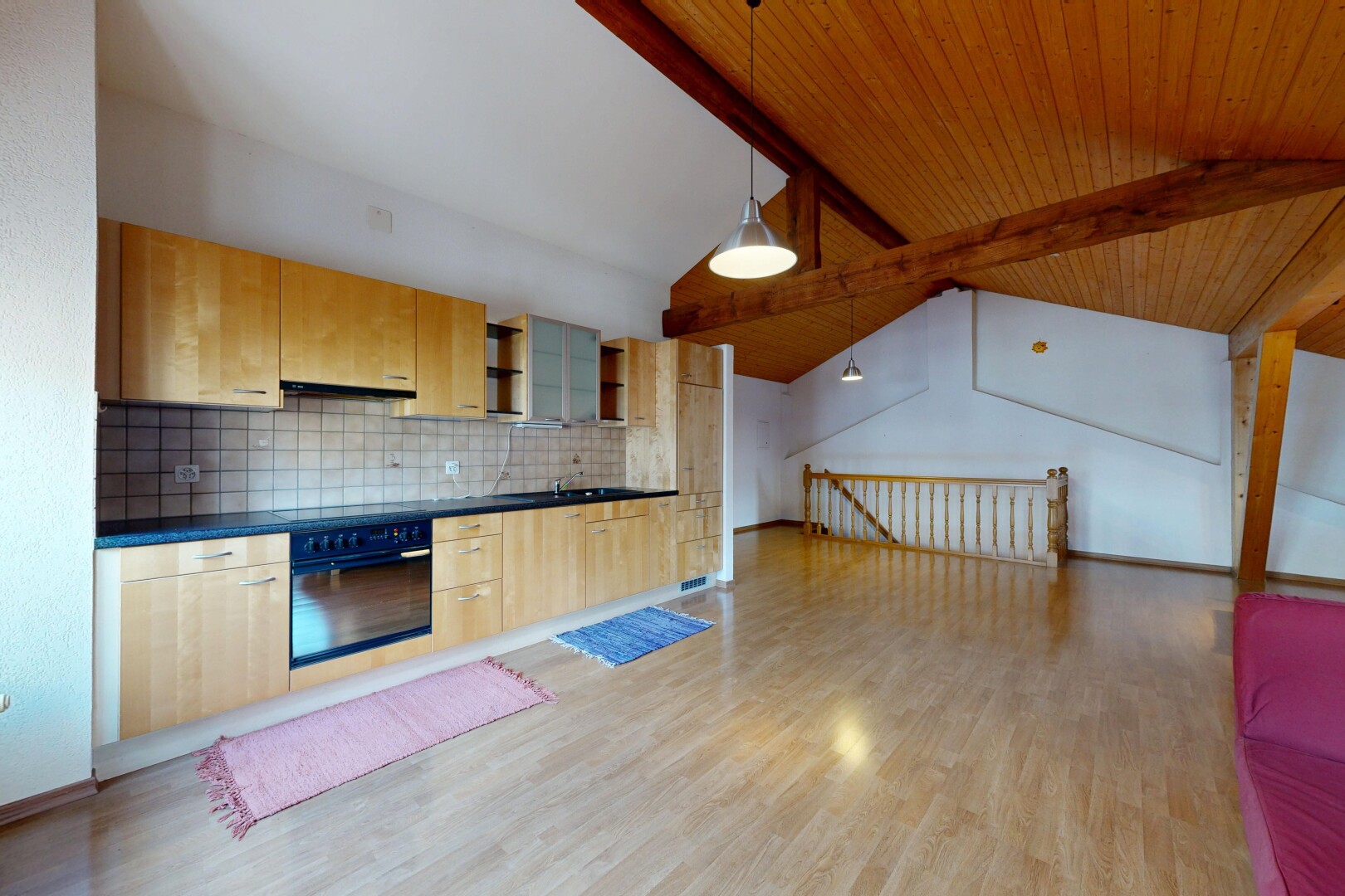 cuisine avec plafond à poutres, beamed ceiling, plans de travail, dark countertops, et armoires marron clair