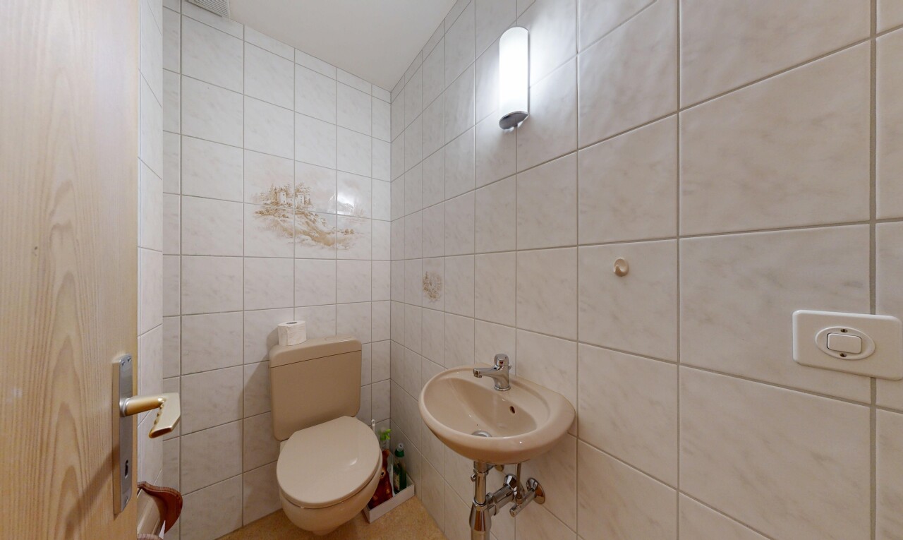 salle de bains avec toilette, tile wall, mur en carrelage, inside property, et évier