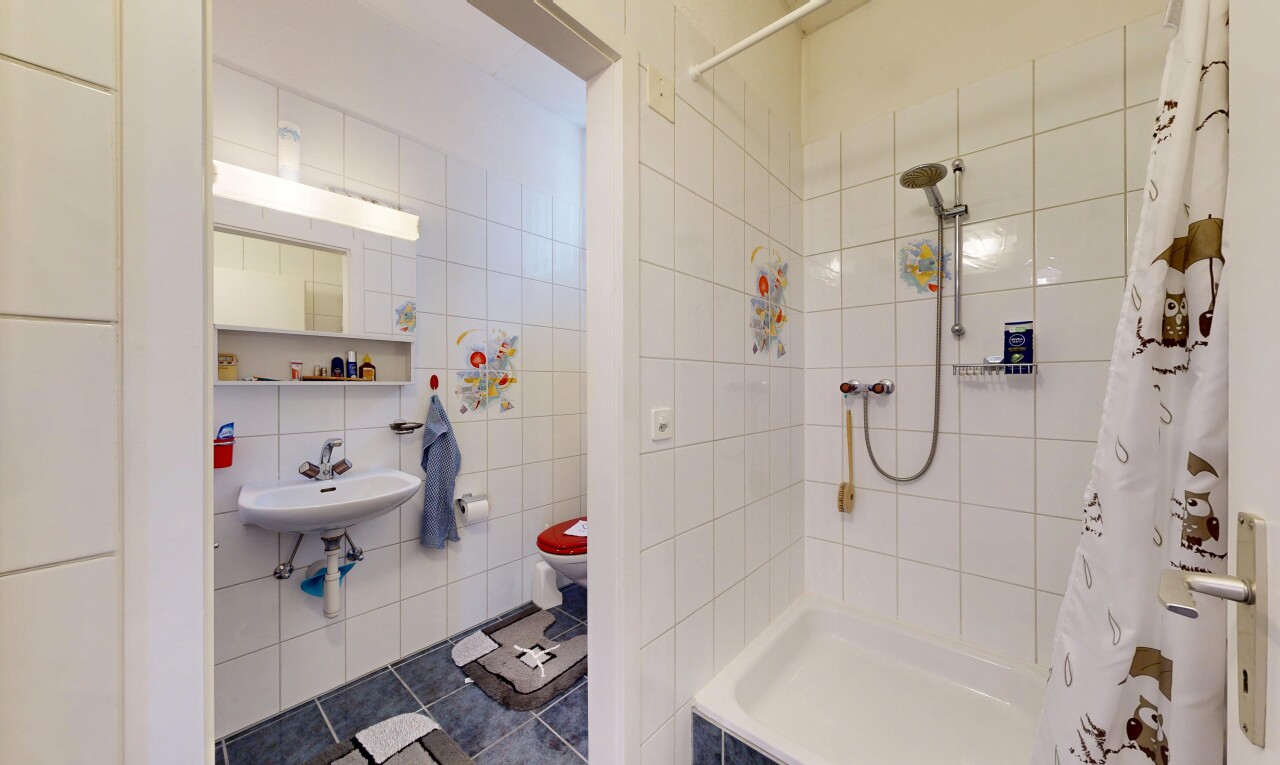 salle de bains avec miroir, douche, toilette, salle de bain complète, et tile wall
